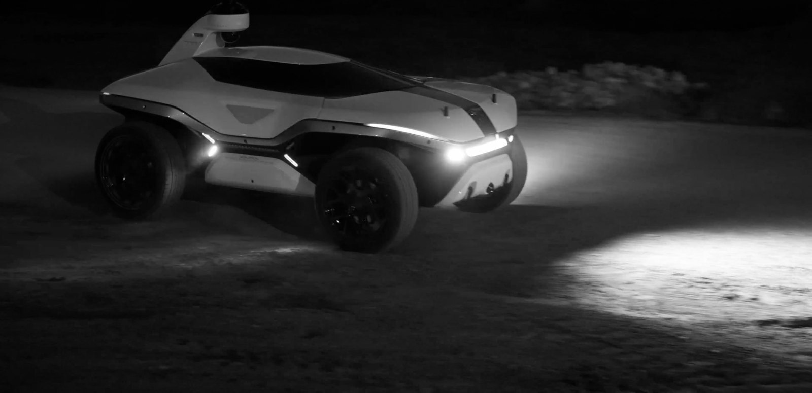 Knightscope K7 Autonomous Security Robot patrolling rough ground at night with headlights on